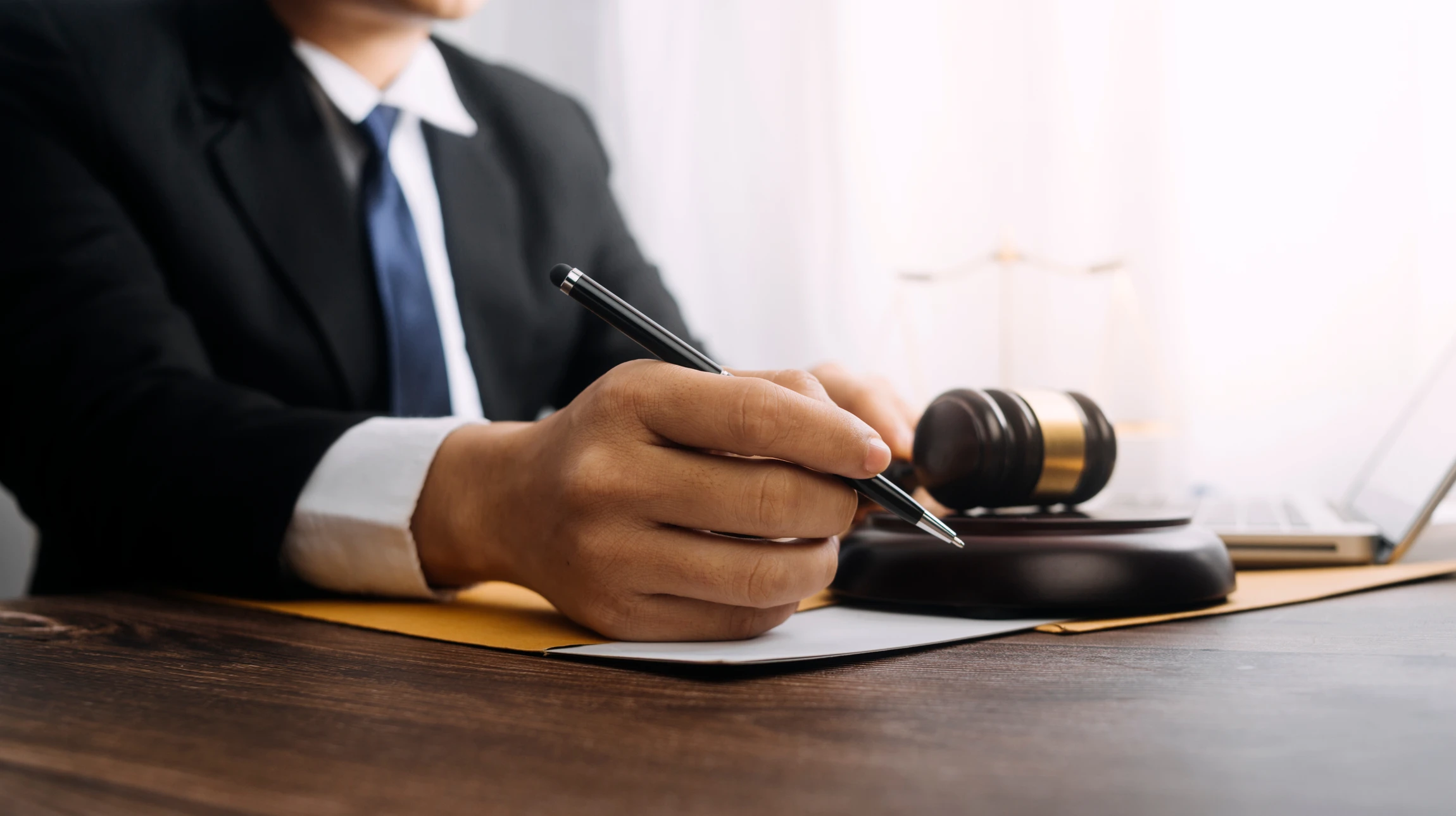 Deux hommes d'affaires en costume et cravate assis à une table de réunion, l'un signant des documents contractuels