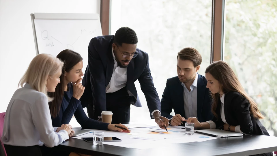 Réunion de travail collaborative dans un bureau moderne avec équipe de professionnels analysant documents et données